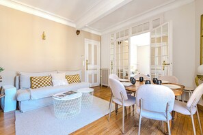 Un salon moderne comprenant un canapé, une table basse et un coin repas avec des chaises.