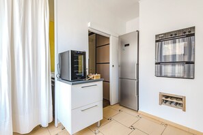 Une cuisine compacte équipée d’un four encastré, d’un réfrigérateur et d’un petit plan de travail.