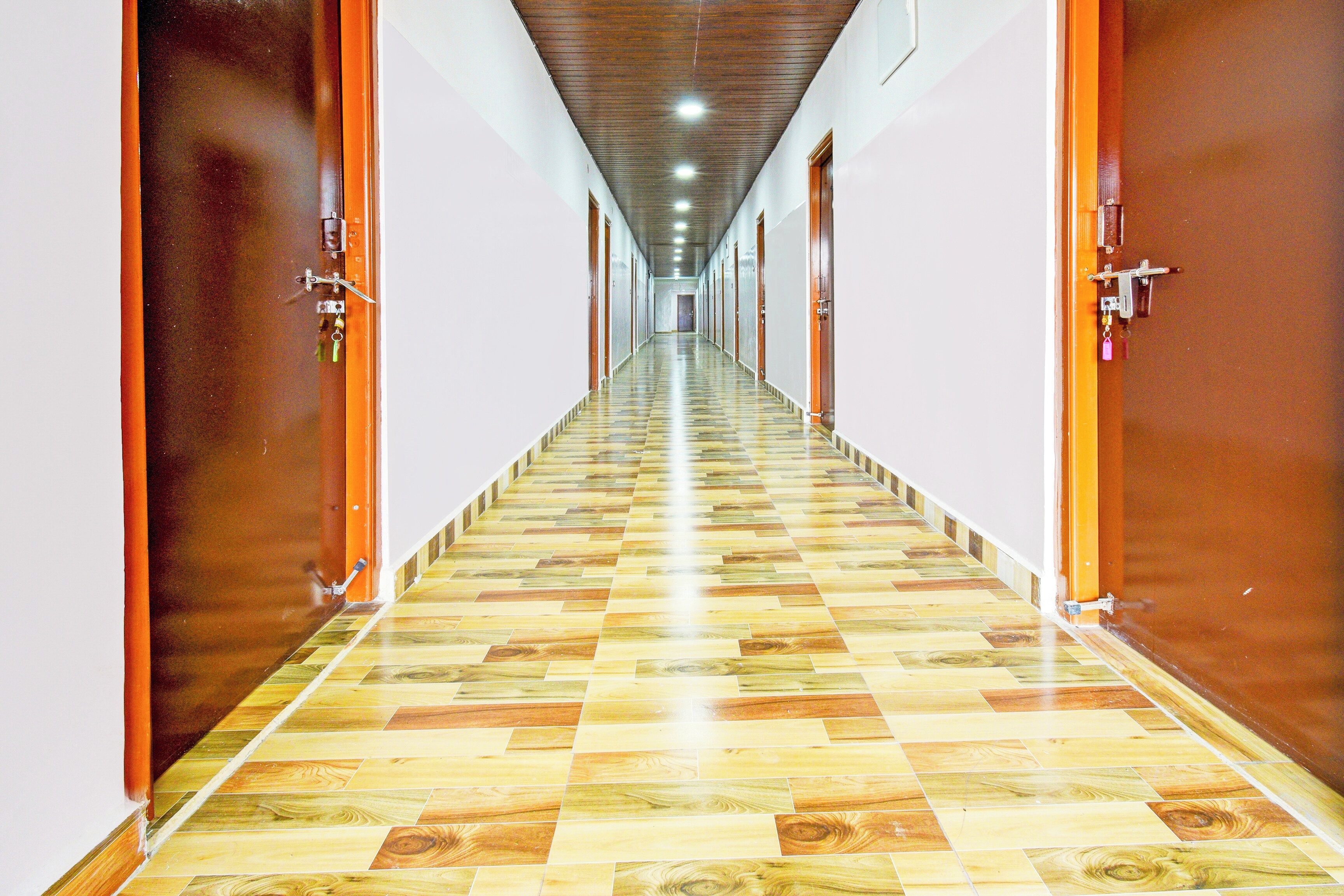 A long hallway with wooden doors on either side and a patterned floor.