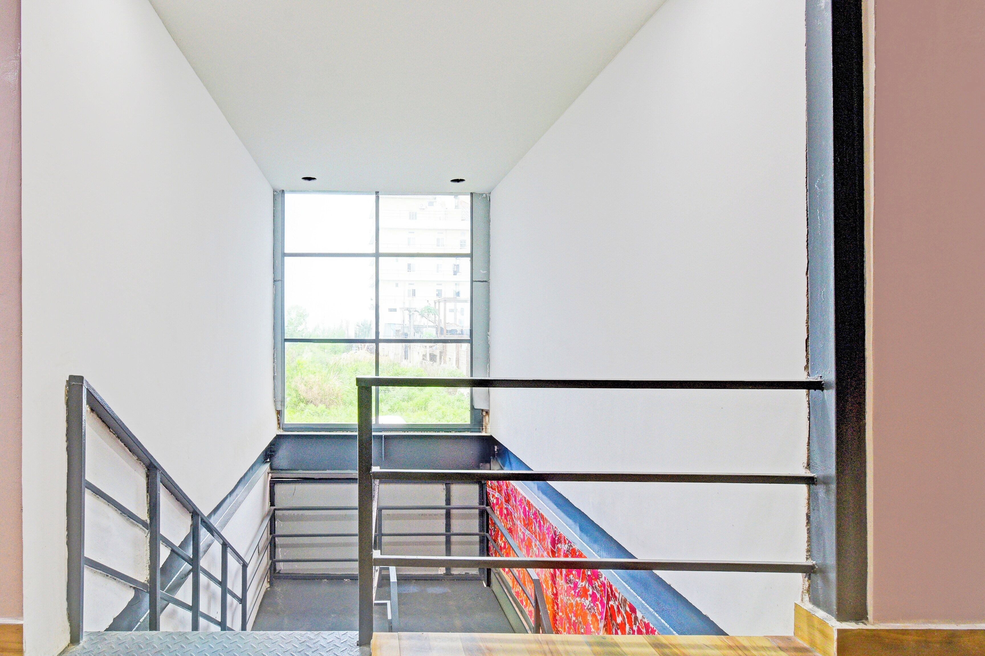 A staircase with metal railings and a view of buildings through a large window.