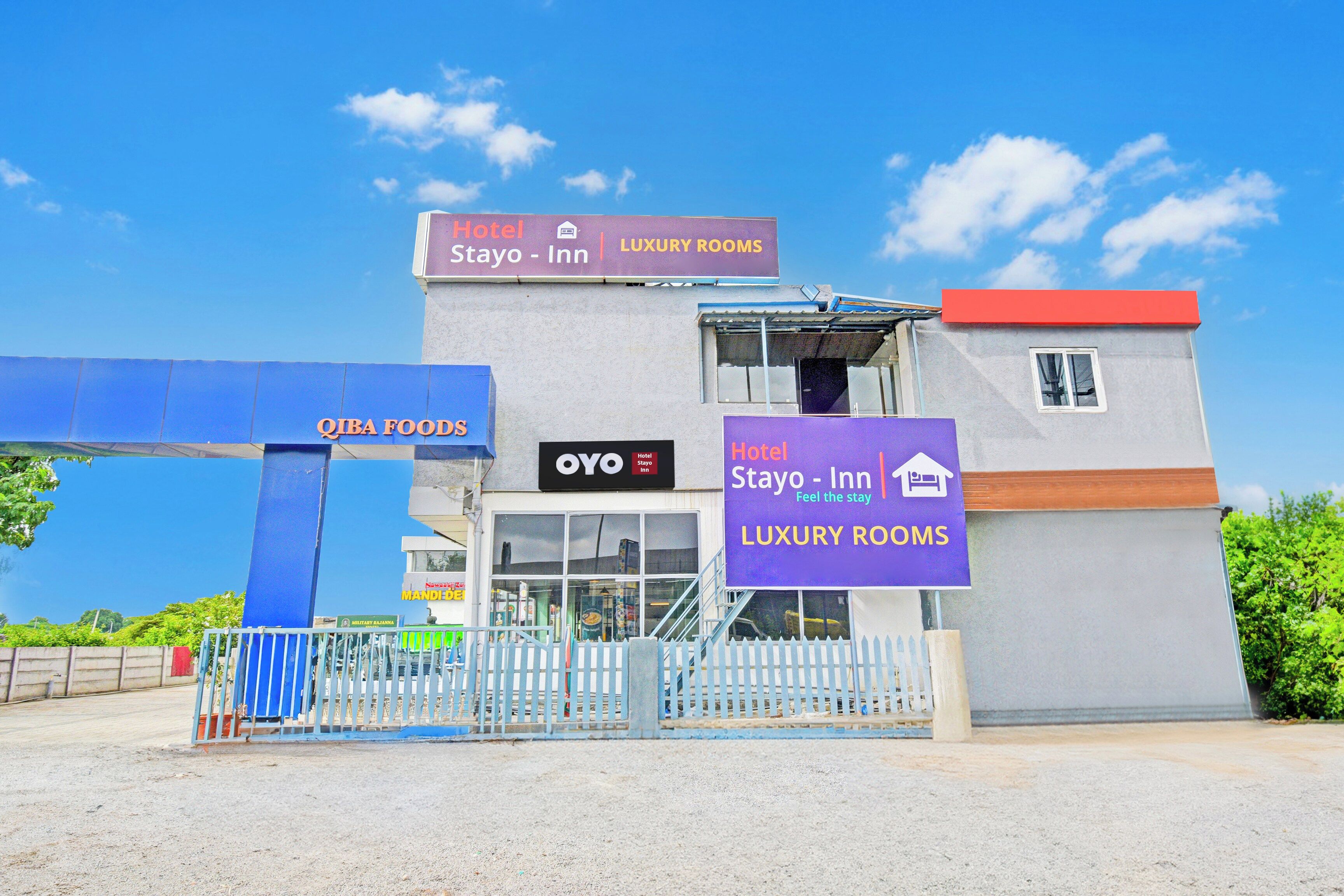 A hotel with a sign indicating luxury rooms and a food outlet named QIBA FOODS.