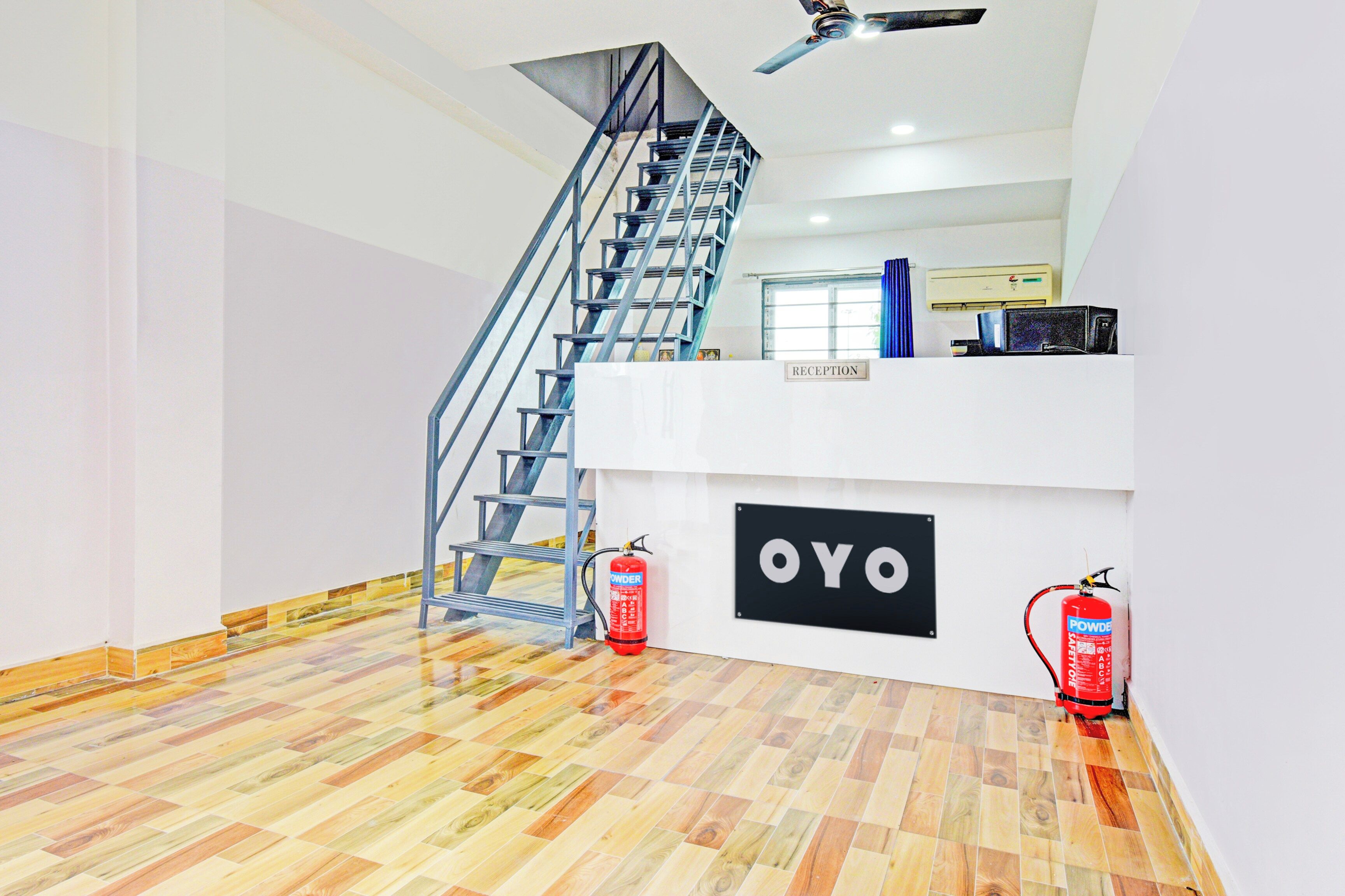 A reception area with a staircase, a fire extinguisher, and a sign labeled 'OYO'.