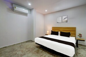 A hotel room with a bed, nightstand, lamp, wall art, and an air conditioning unit. - Hotel O by OYO Living Tree In (Hyderabad)