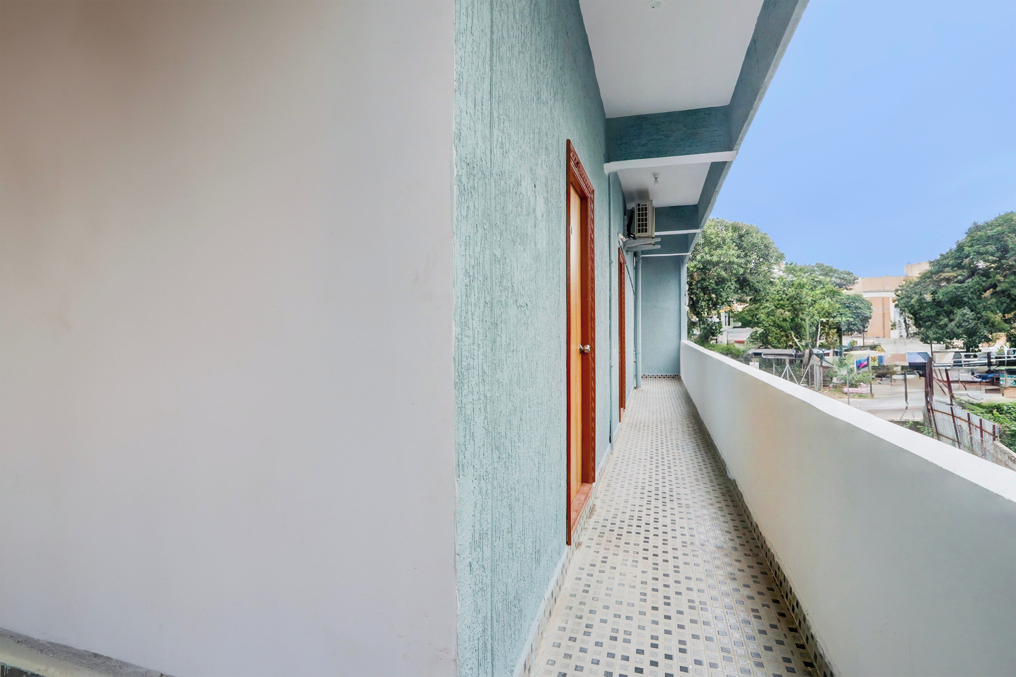 A narrow balcony with a patterned floor, a door, and a window.