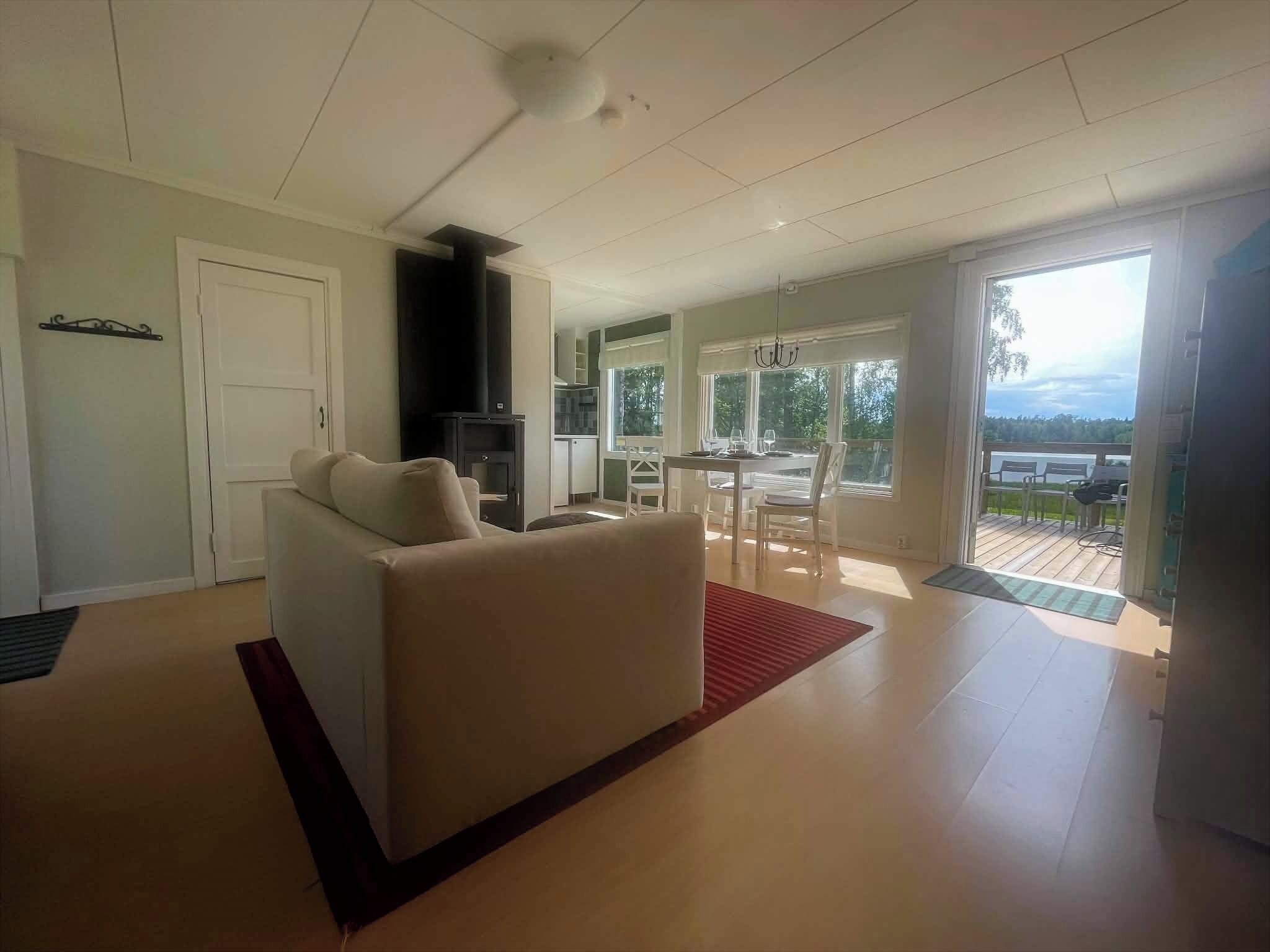 A modern living room with a sofa, a dining area with a table and chairs, and a kitchen area with cabinets and a stove.
