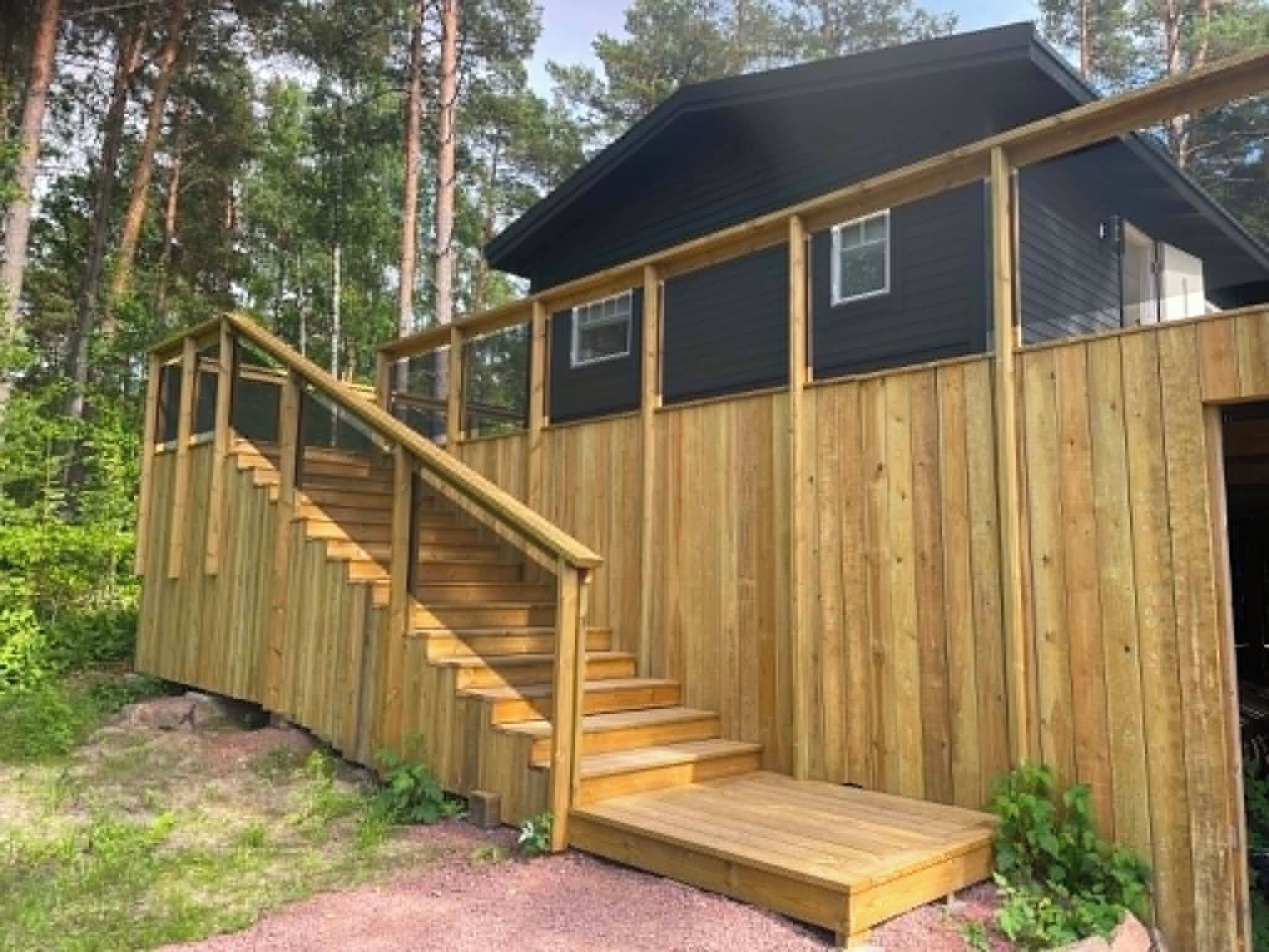 Una cabaña de madera con una escalera que lleva a una terraza.