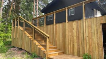 Una cabaña de madera con una escalera que lleva a una terraza.