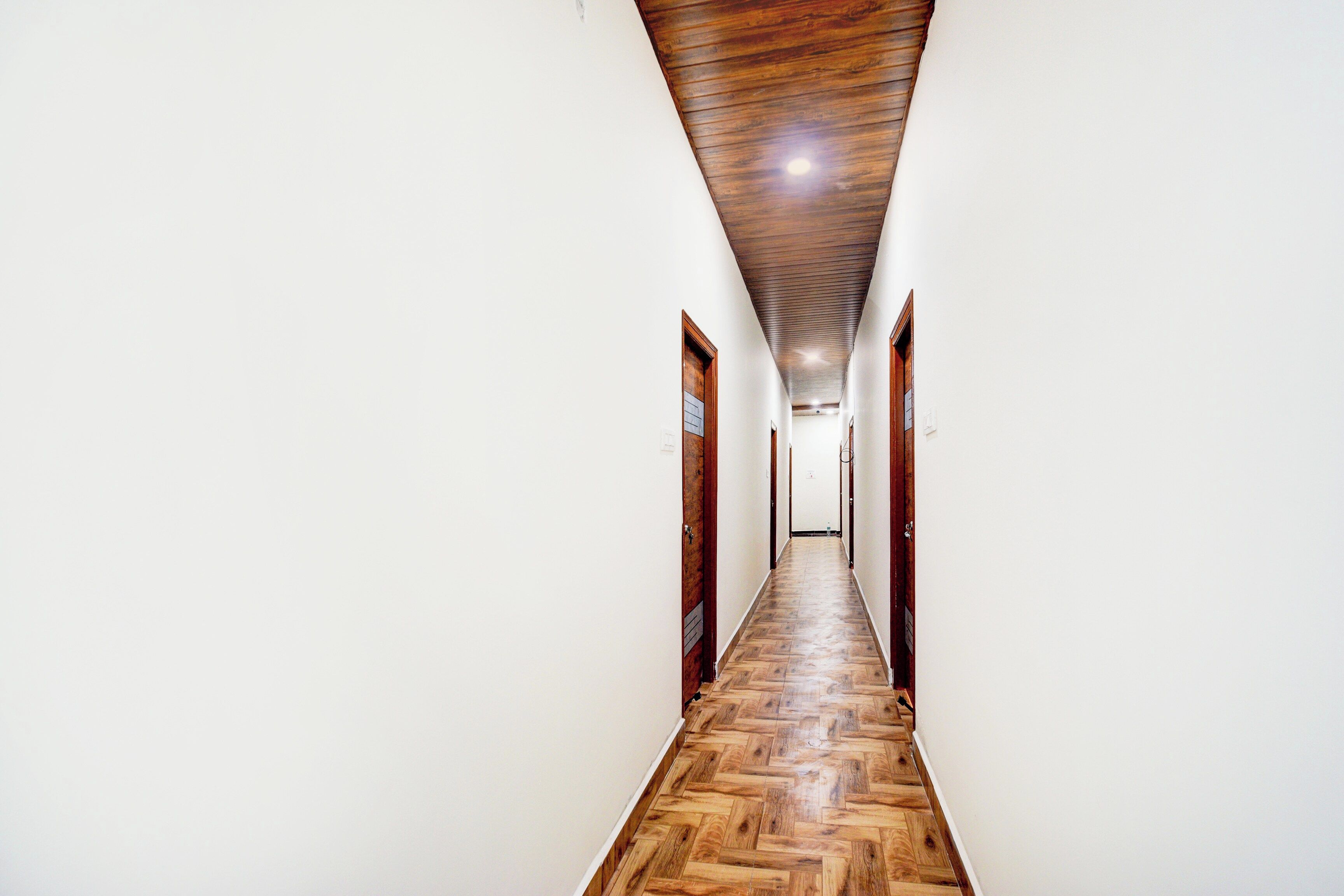 A long, narrow hallway with wooden flooring and white walls.