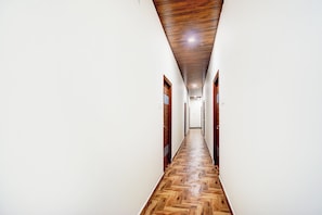 A long, narrow hallway with wooden flooring and white walls. - HOTEL O LIVING TREE (Hyderabad)