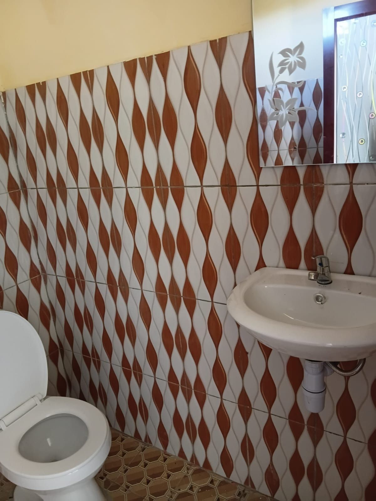 Un baño con inodoro, lavamanos y azulejos decorativos.