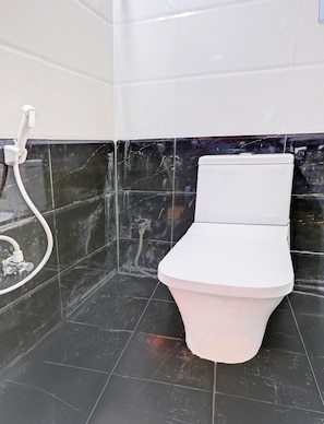 A bathroom with a toilet, a shower, and a tiled floor. - Hotel O by OYO M&N Grand (Hyderabad)