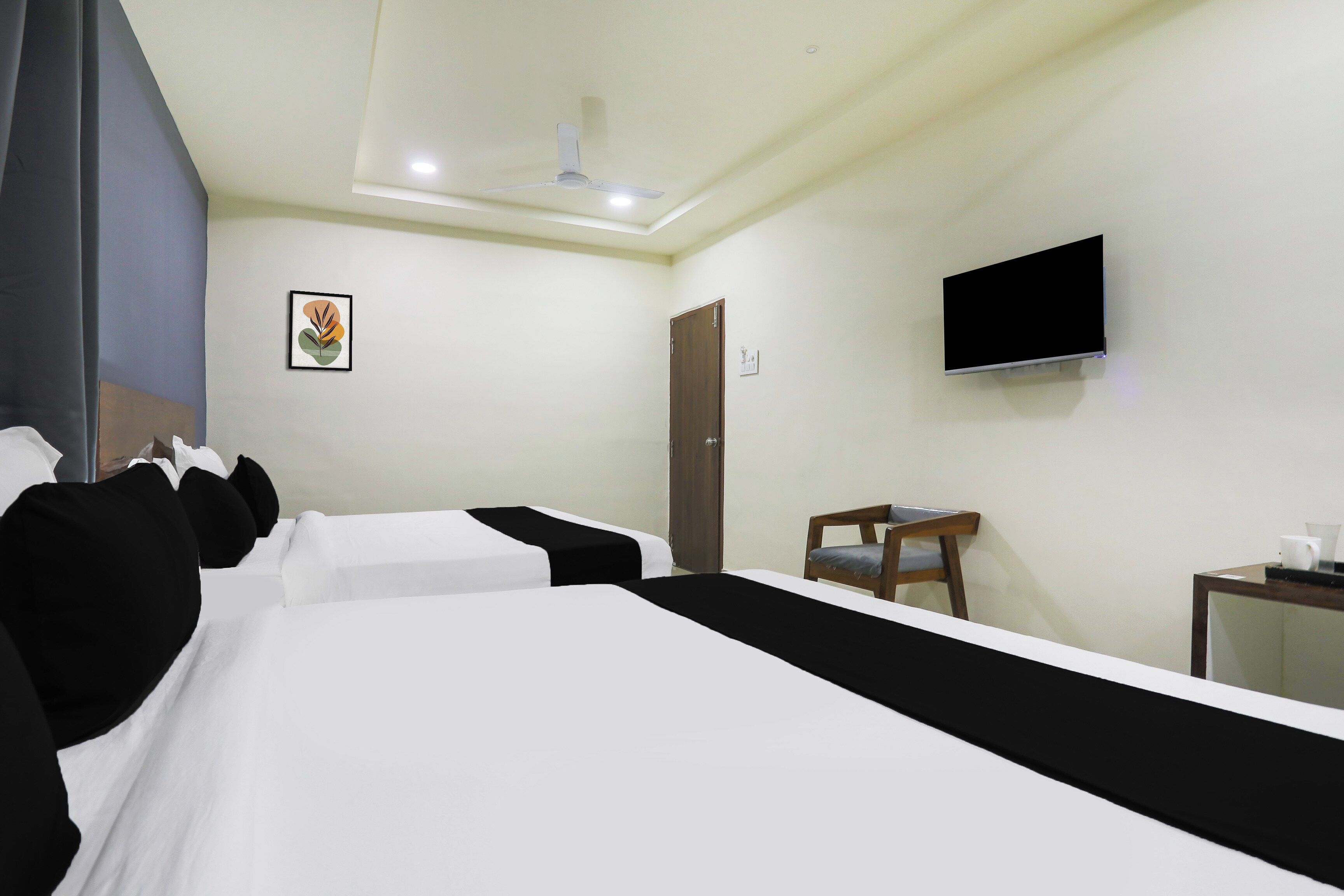 A hotel room with a bed, a desk, a chair, a television, and a ceiling fan.