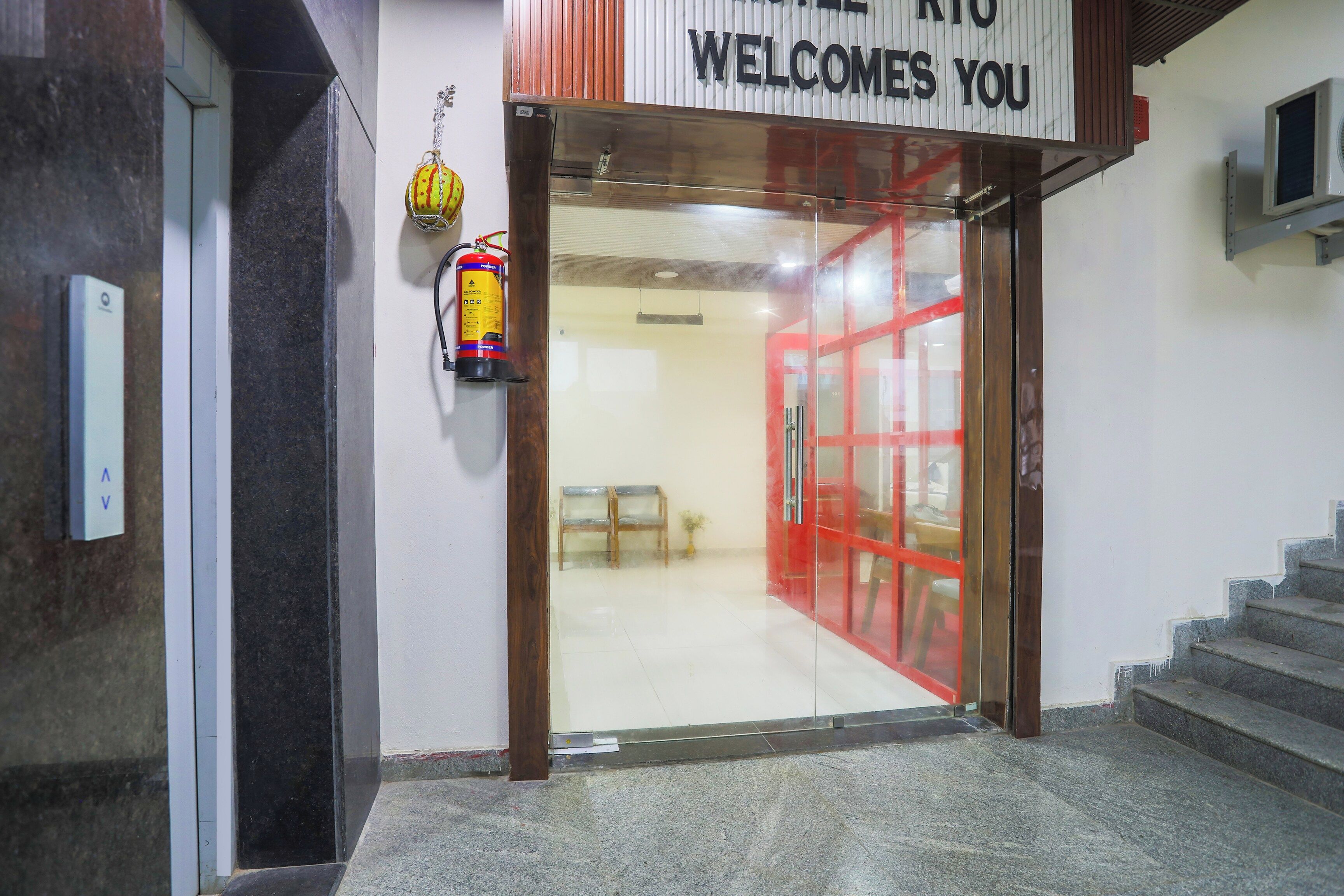 A hotel entrance with a sign that reads 'WELCOME YOU' and a fire extinguisher mounted on the wall.