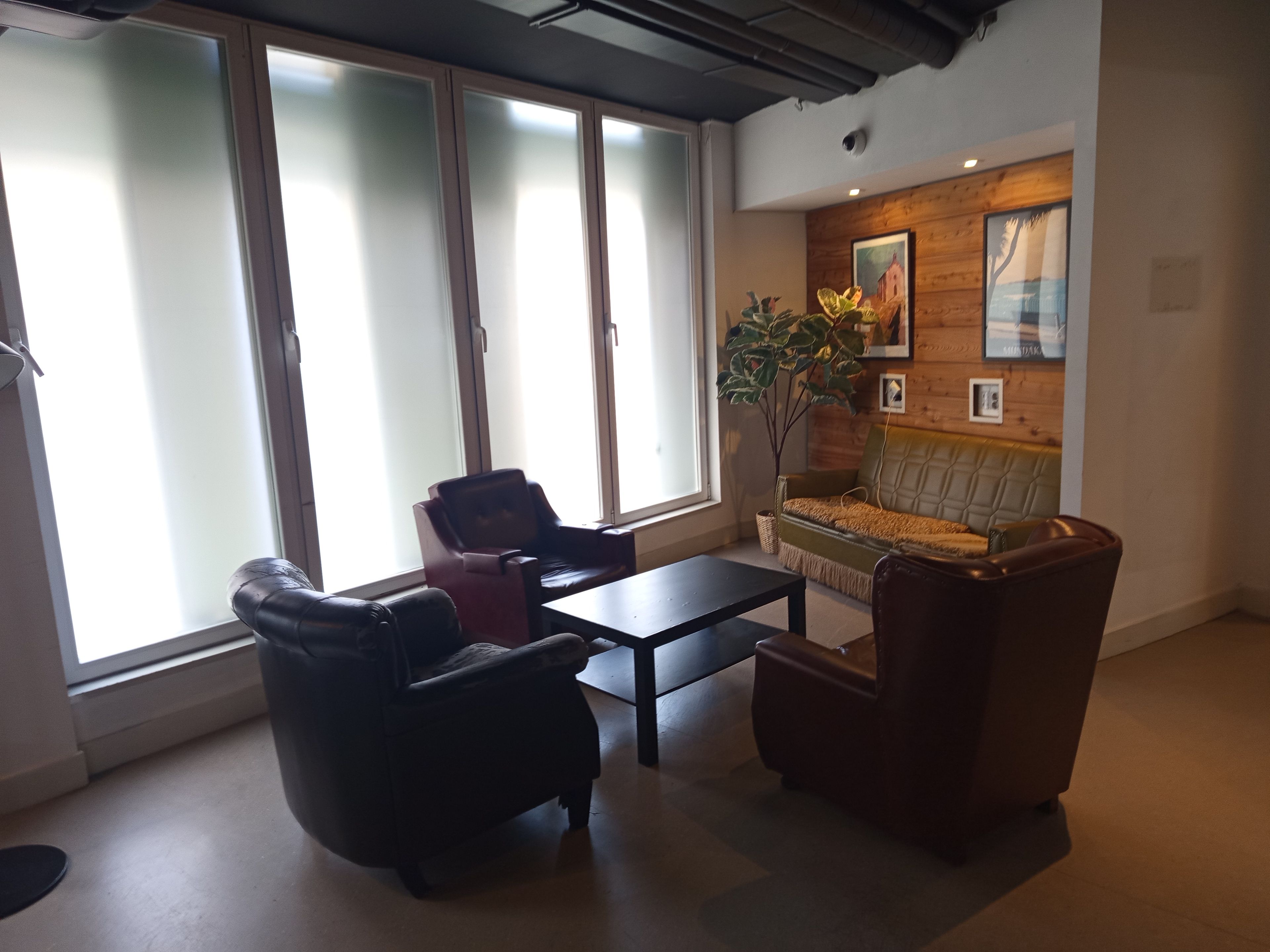 Una sala de estar moderna con un sofá, dos sillones, una mesa de centro y un ventanal con vidrio esmerilado.
