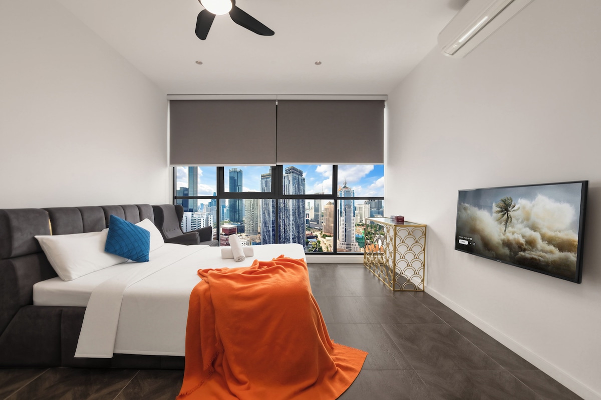 Una habitación de hotel moderna con un ventanal grande, una cama, un televisor y un ventilador de techo.