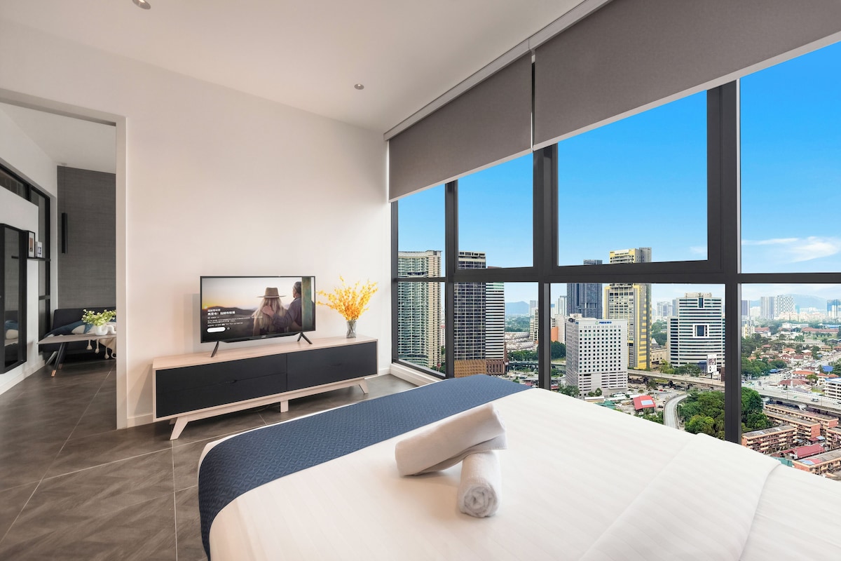Un dormitorio moderno con una cama grande, un televisor y vistas a la ciudad.
