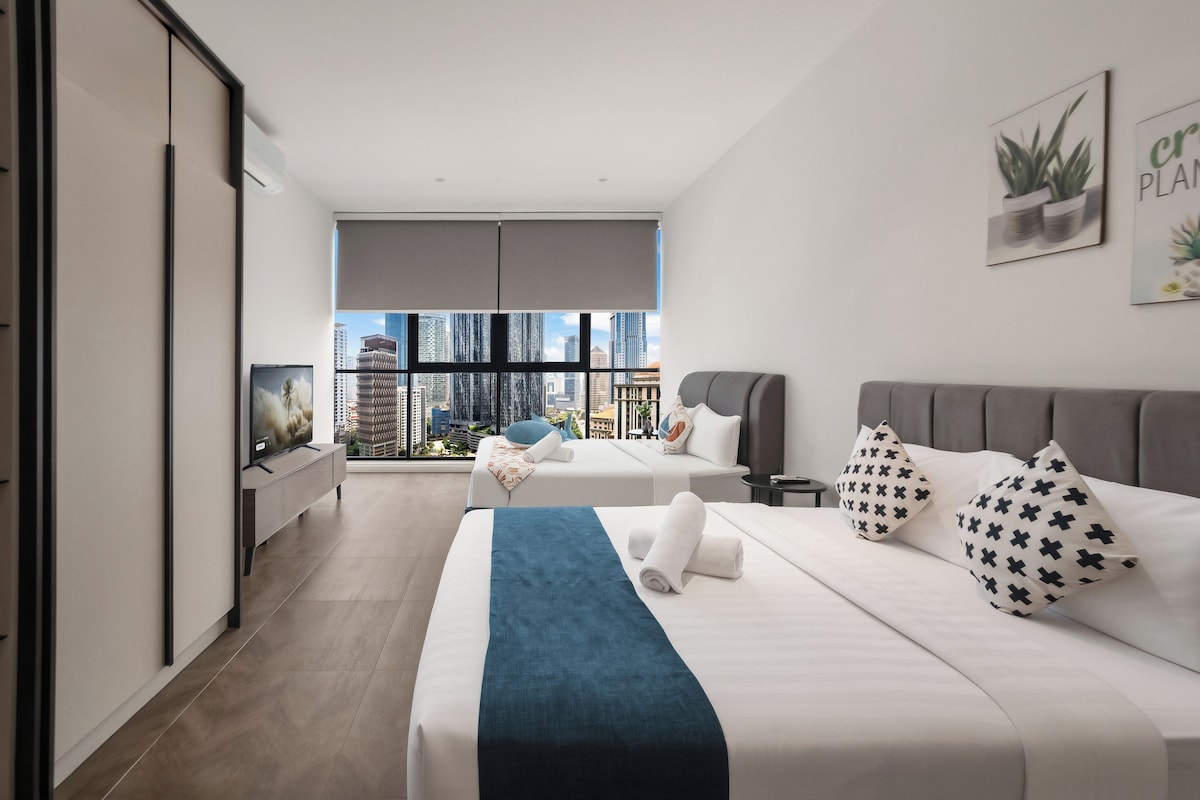Habitación de hotel moderna con una cama grande, una cama individual, televisión y vista a la ciudad.
