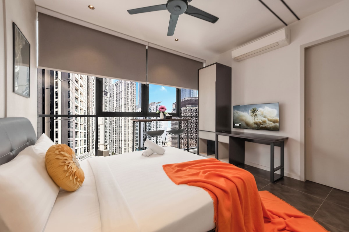 Habitación de hotel moderna con cama, televisor y vistas a rascacielos.