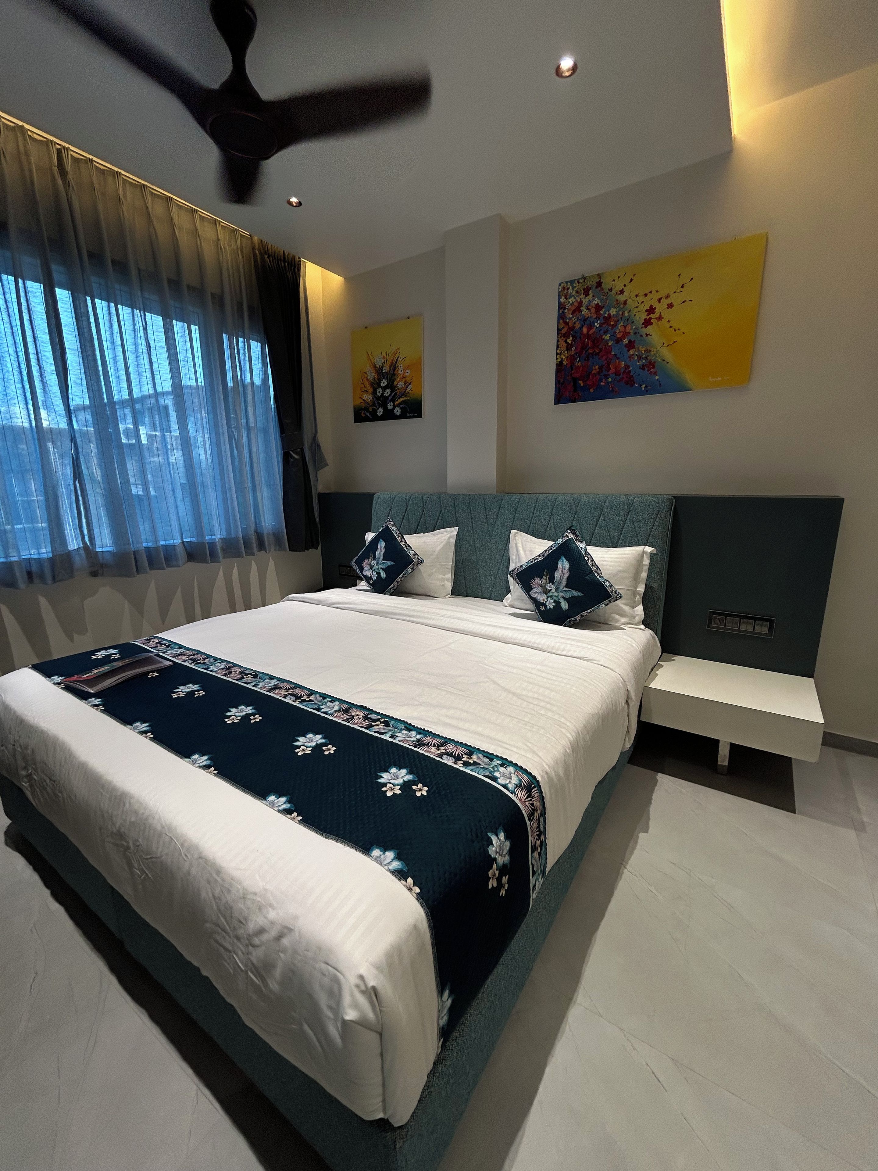 Un dormitorio moderno con una cama grande, una mesita de noche y un ventilador de techo.