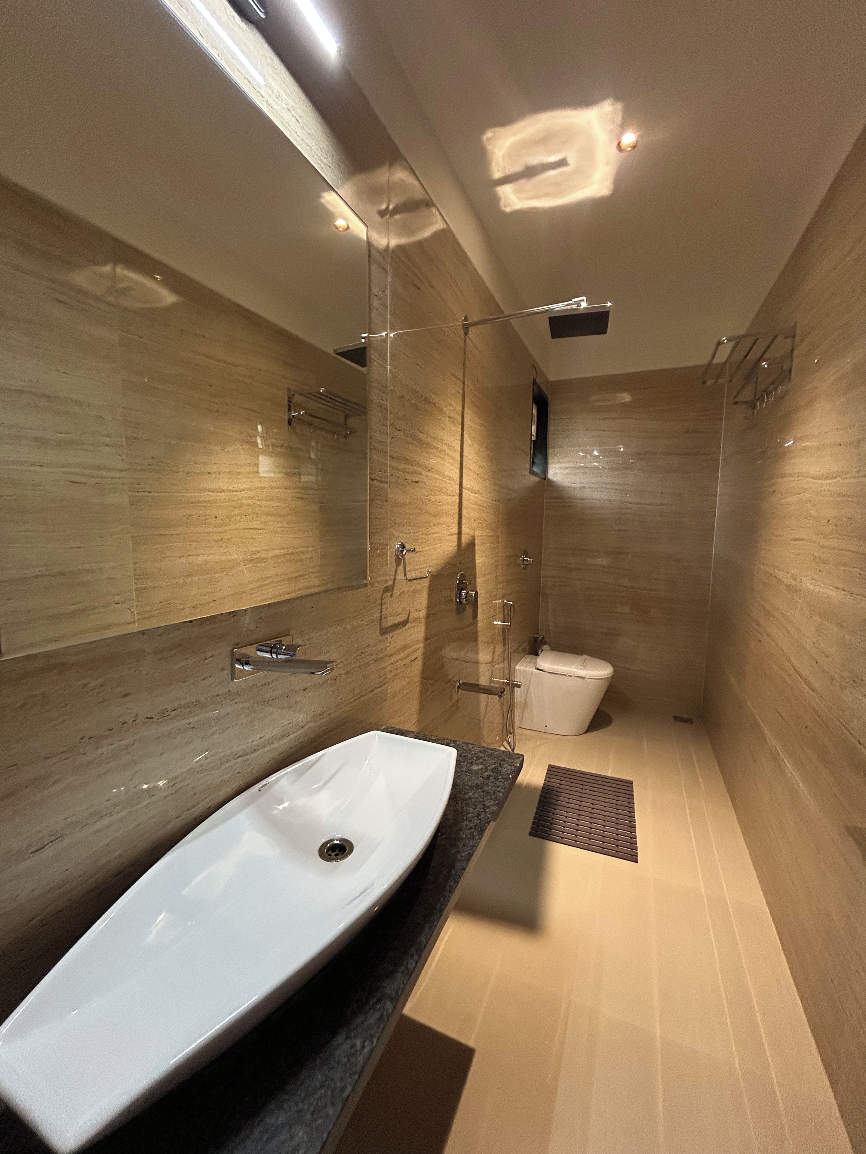 A modern bathroom with a large white sink, a glass shower enclosure, and a toilet.