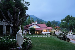 A house with a red-tiled roof, surrounded by a well-maintained garden and a white fence. - Miln Town by Zari (Coonoor)