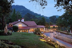 A house with a red-tiled roof, surrounded by a well-maintained garden and a white picket fence. - Miln Town by Zari (Coonoor)