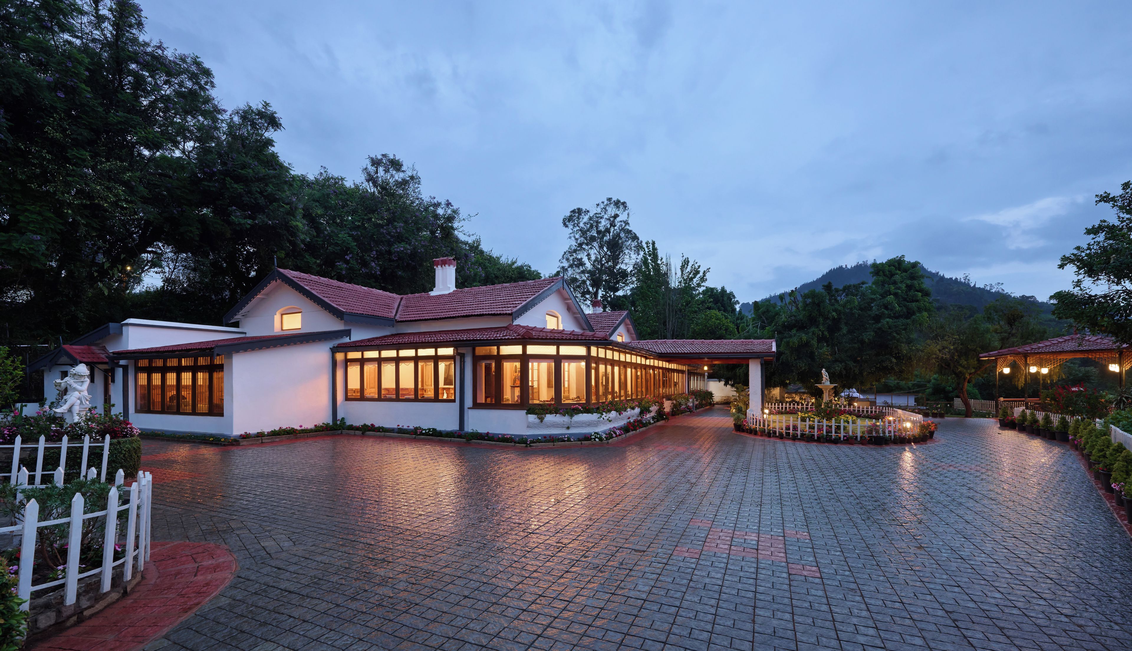A two-story building with a red-tiled roof, large windows, and a paved driveway.