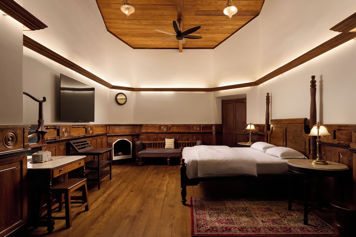 A hotel room with a bed, desk, chair, and a large mirror.