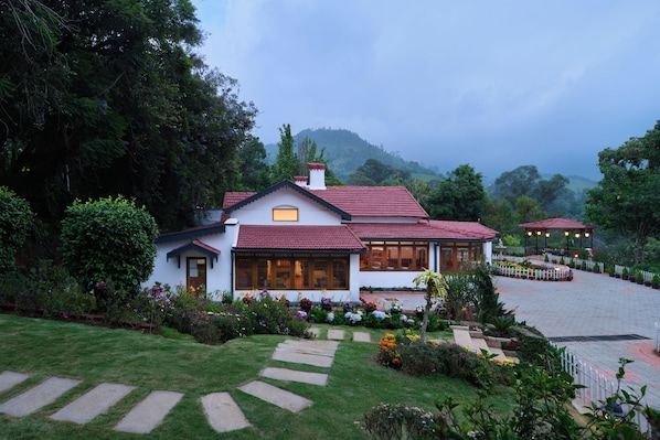 A two-story house with a red-tiled roof, surrounded by lush greenery and a well-maintained garden. - Miln Town by Zari (Coonoor)