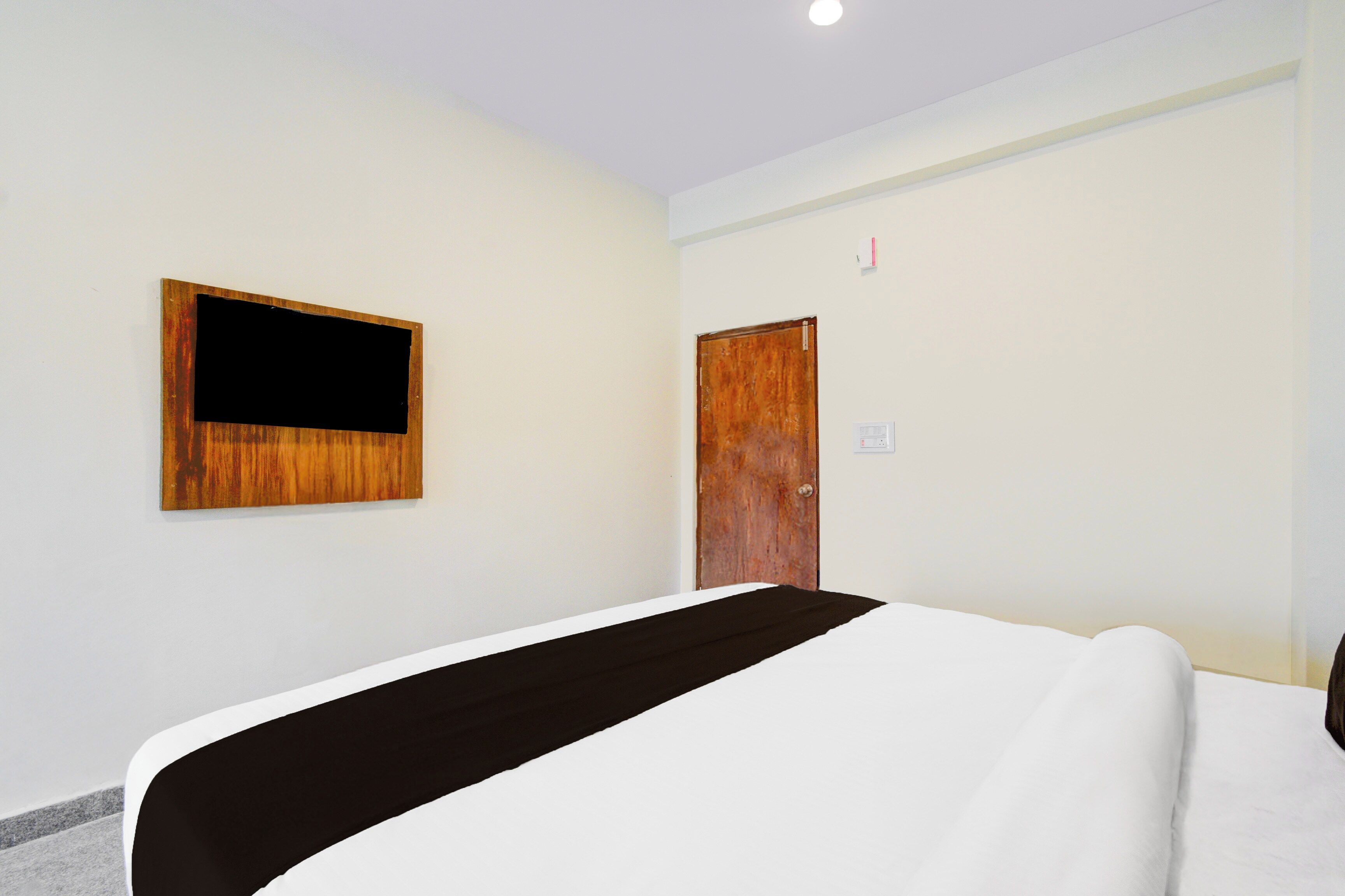 Une chambre d’hôtel avec un lit, une porte en bois et un téléviseur fixé au mur.