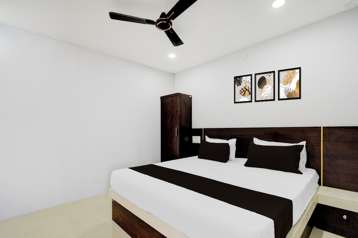 A bedroom with a bed, a wardrobe, a ceiling fan, and three framed artworks on the wall.