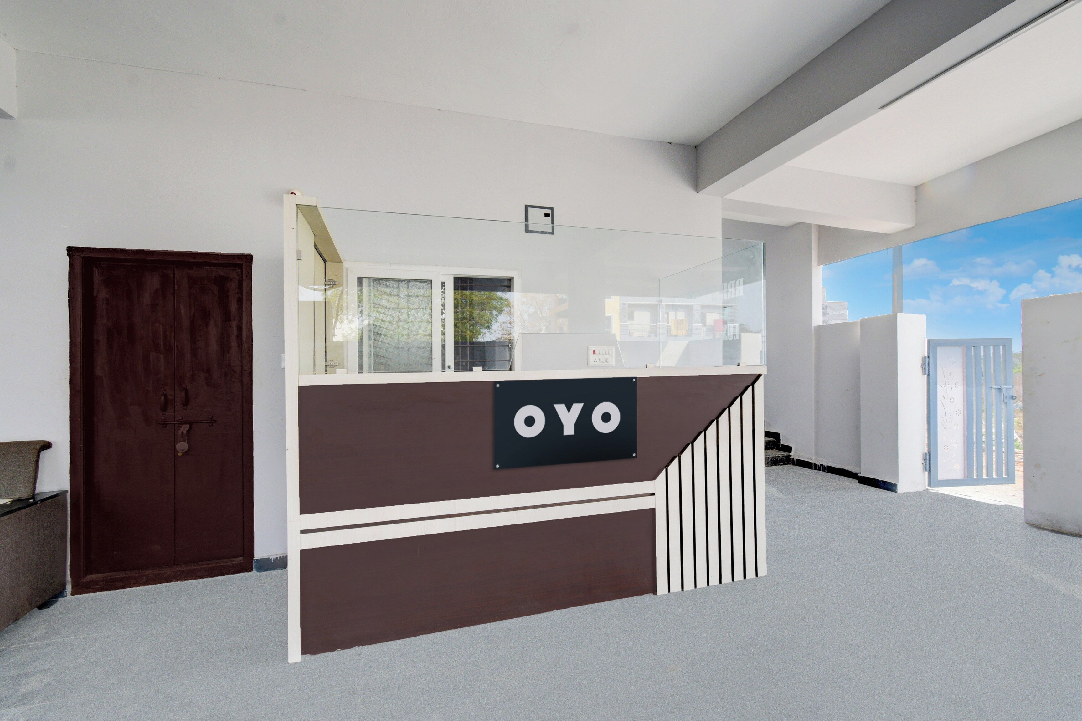 A reception desk with a sign reading 'OYO' in a modern interior with white walls and a large window.