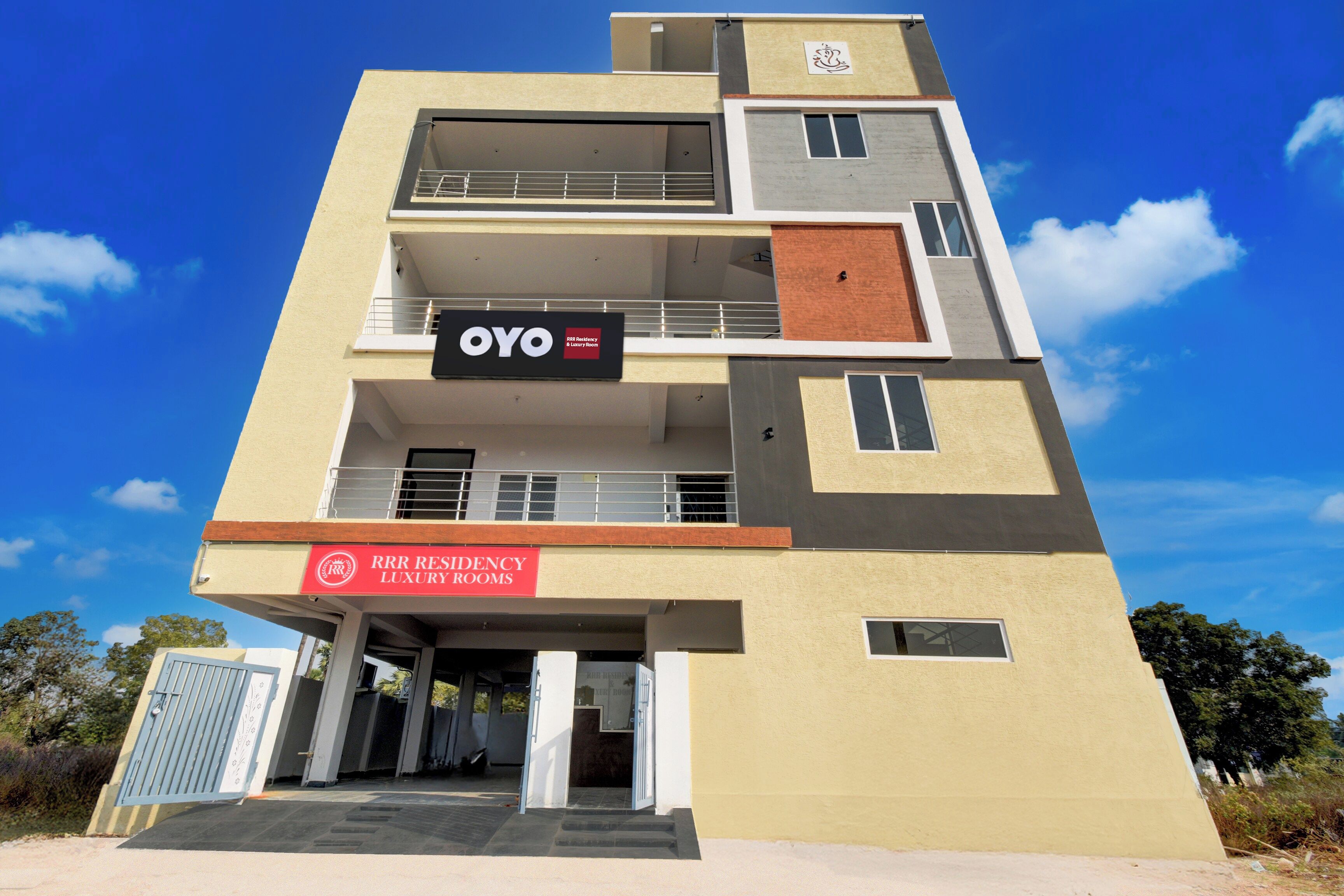 Ein mehrstöckiges Gebäude mit einem Schild für 'OYO RRR Residency & Luxury Rooms' im Erdgeschoss.