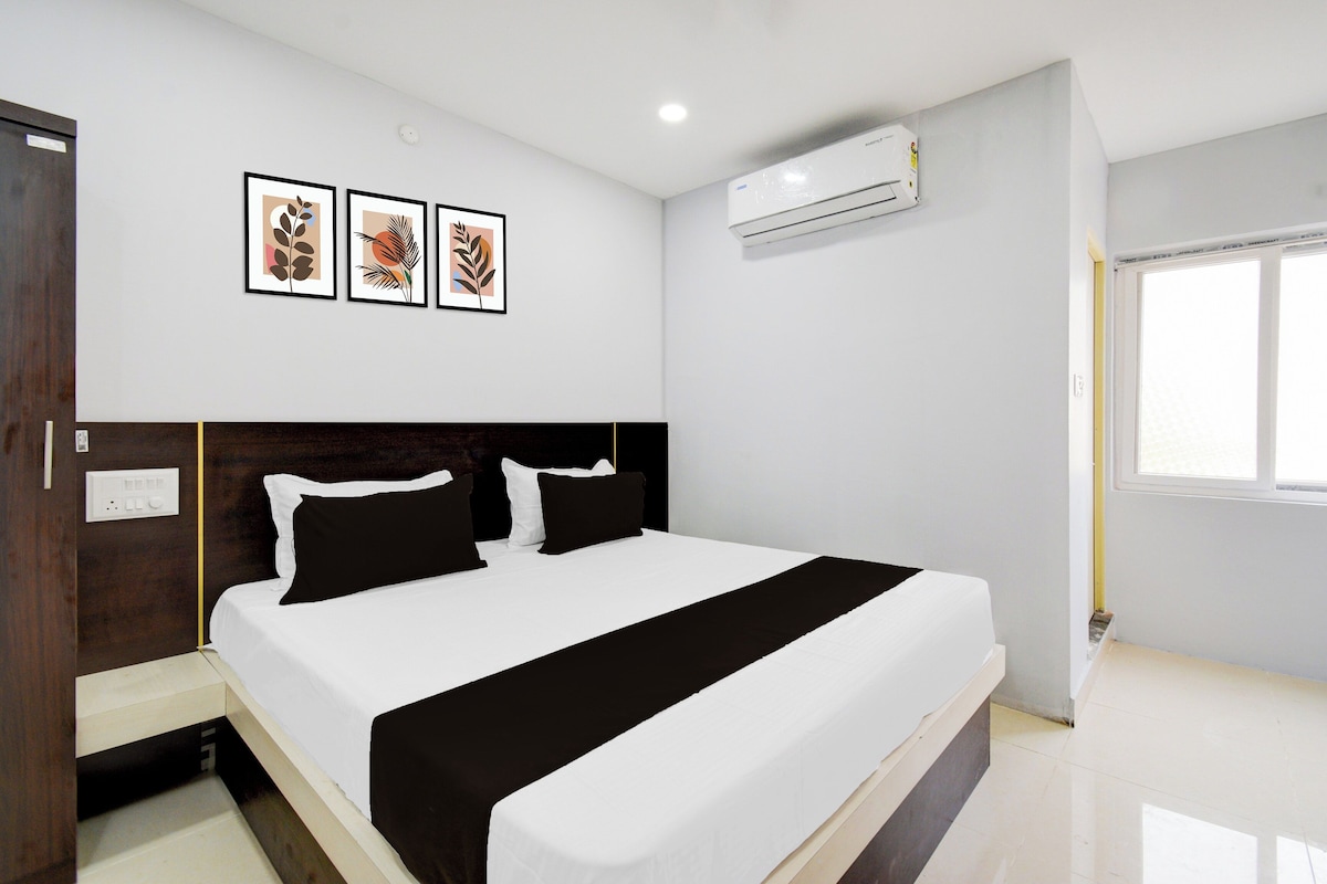 A bedroom with a bed, a nightstand, a wall-mounted air conditioner, and three framed pictures.