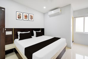 A bedroom with a bed, a nightstand, a wall-mounted air conditioner, and three framed pictures. - Hotel O RRR Residency & Luxury rooms (Hyderabad)