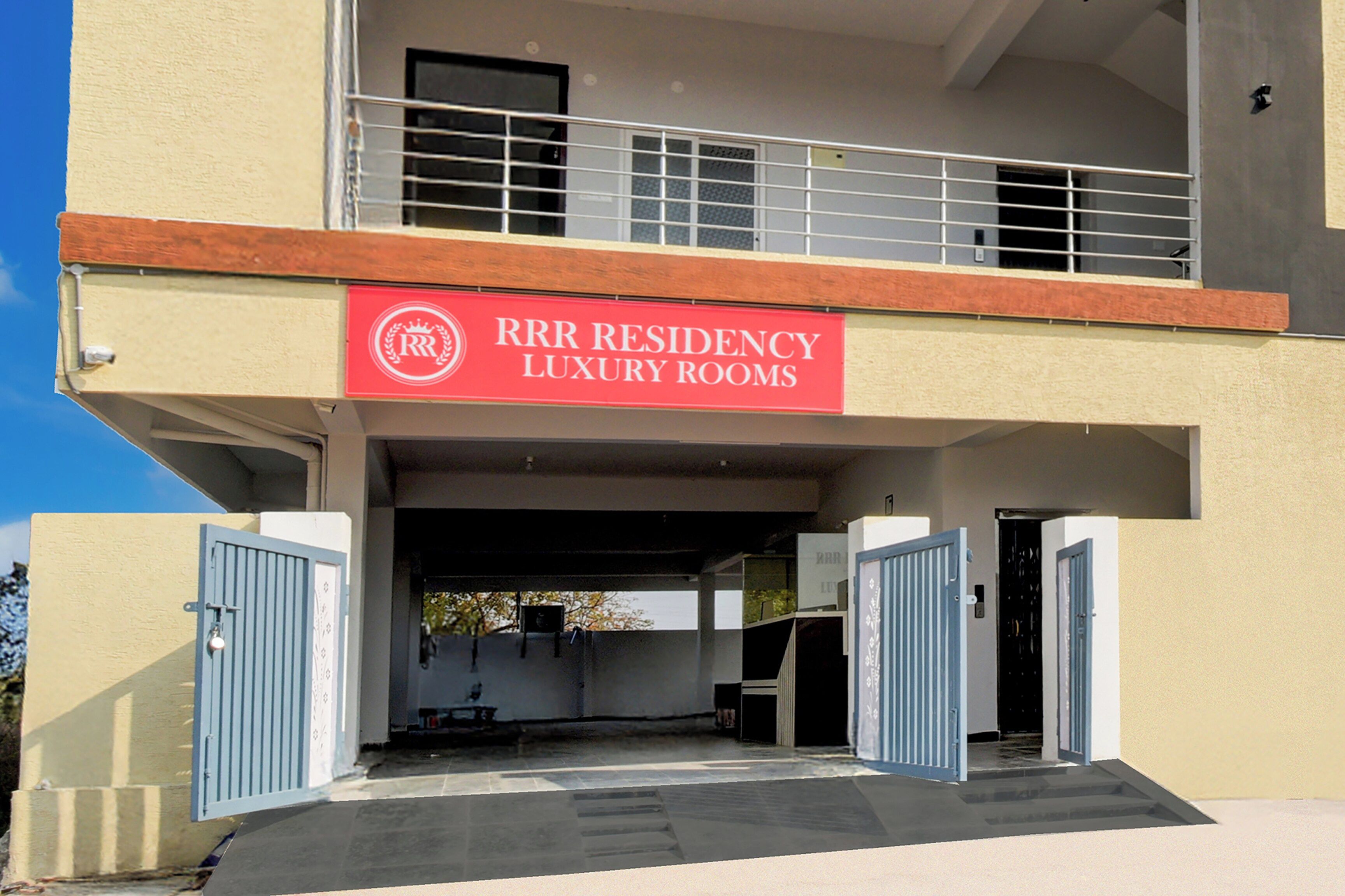 A building with a sign for 'RRR Residency Luxury Rooms' and a gated entrance.