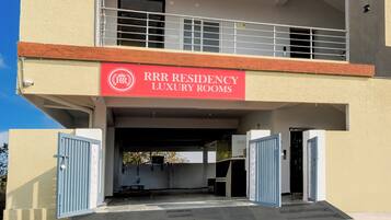 Ein Gebäude mit einem Schild für 'RRR Residency Luxury Rooms' und einem bewachten Eingang.