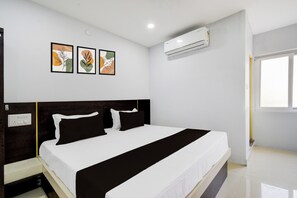 A hotel room with a bed, a nightstand, a wall-mounted air conditioner, and two framed artworks. - Hotel O RRR Residency & Luxury rooms (Hyderabad)