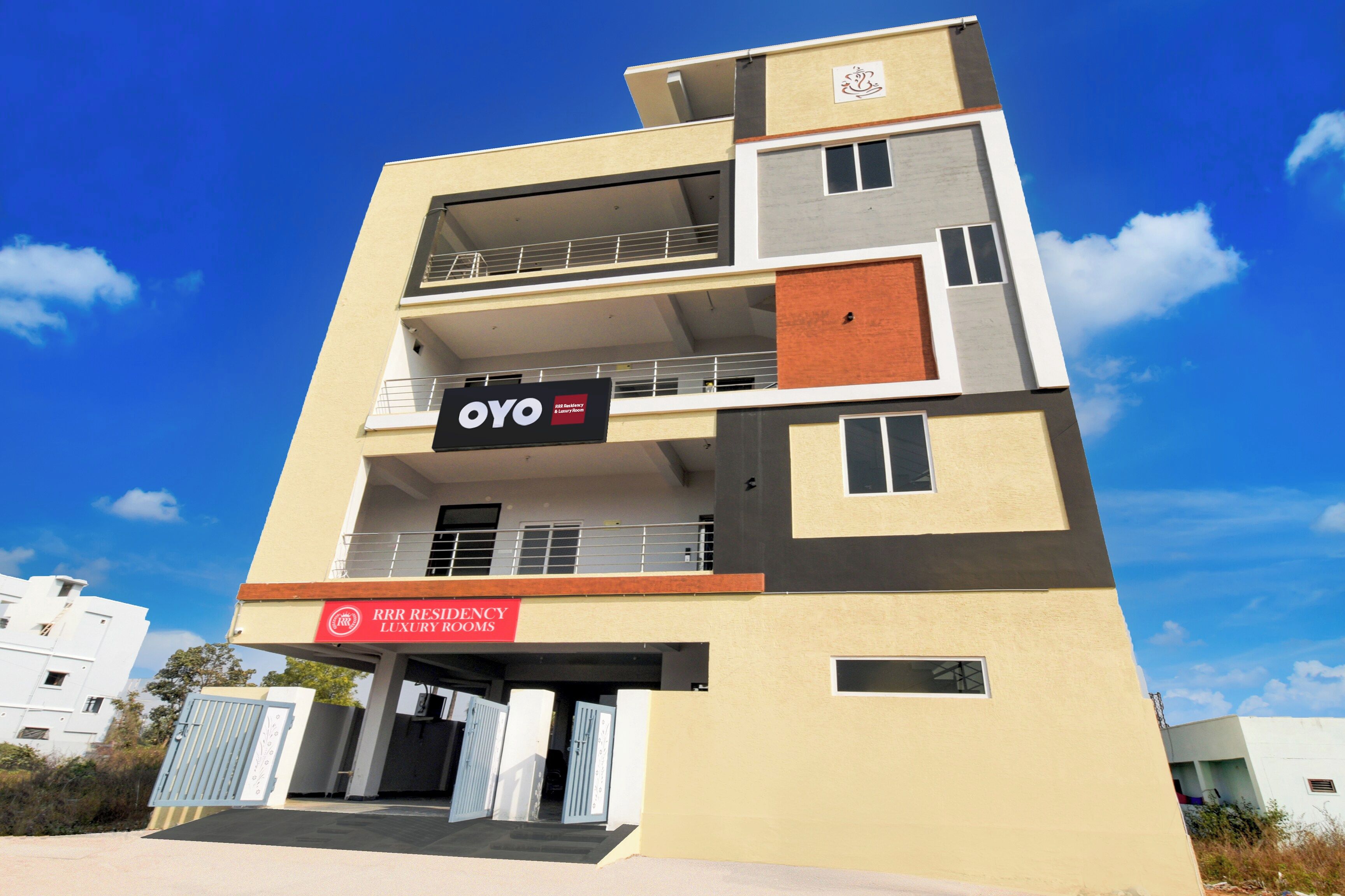 A multi-story building with balconies, a sign for 'OYO' indicating a hotel or lodging service, and a sign for 'RRR Residency Luxury Rooms' suggesting a specific type of accommodation.