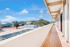 A balcony with a view of a building and trees, a tiled floor, and a clear sky. - Hotel O by OYO Sansar (Hyderabad)