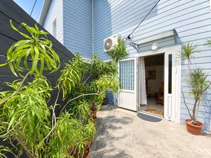 Il s’agit d’une propriété résidentielle dotée d’un patio couvert, de plantes en pot et d’une porte-fenêtre coulissante donnant sur un espace intérieur.