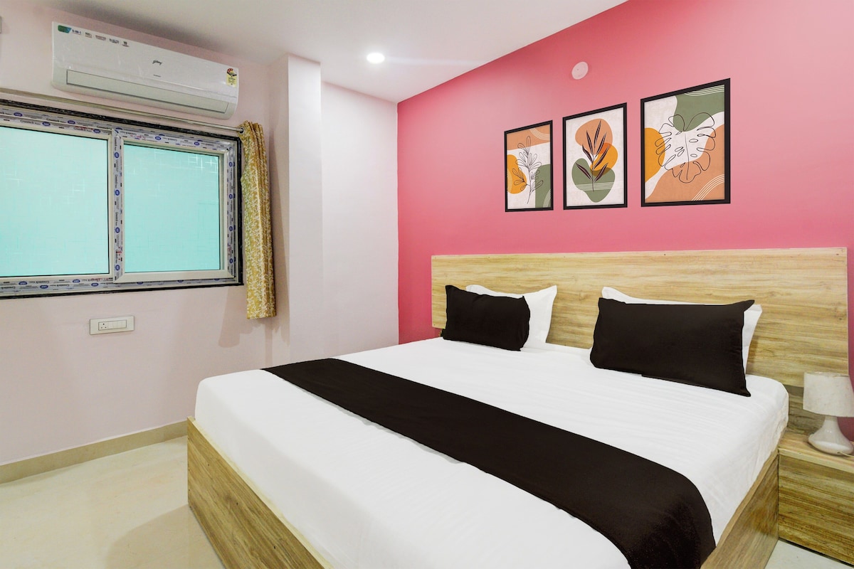 Una habitación de hotel con cama, ventana con cortinas, aire acondicionado y decoración en la pared.