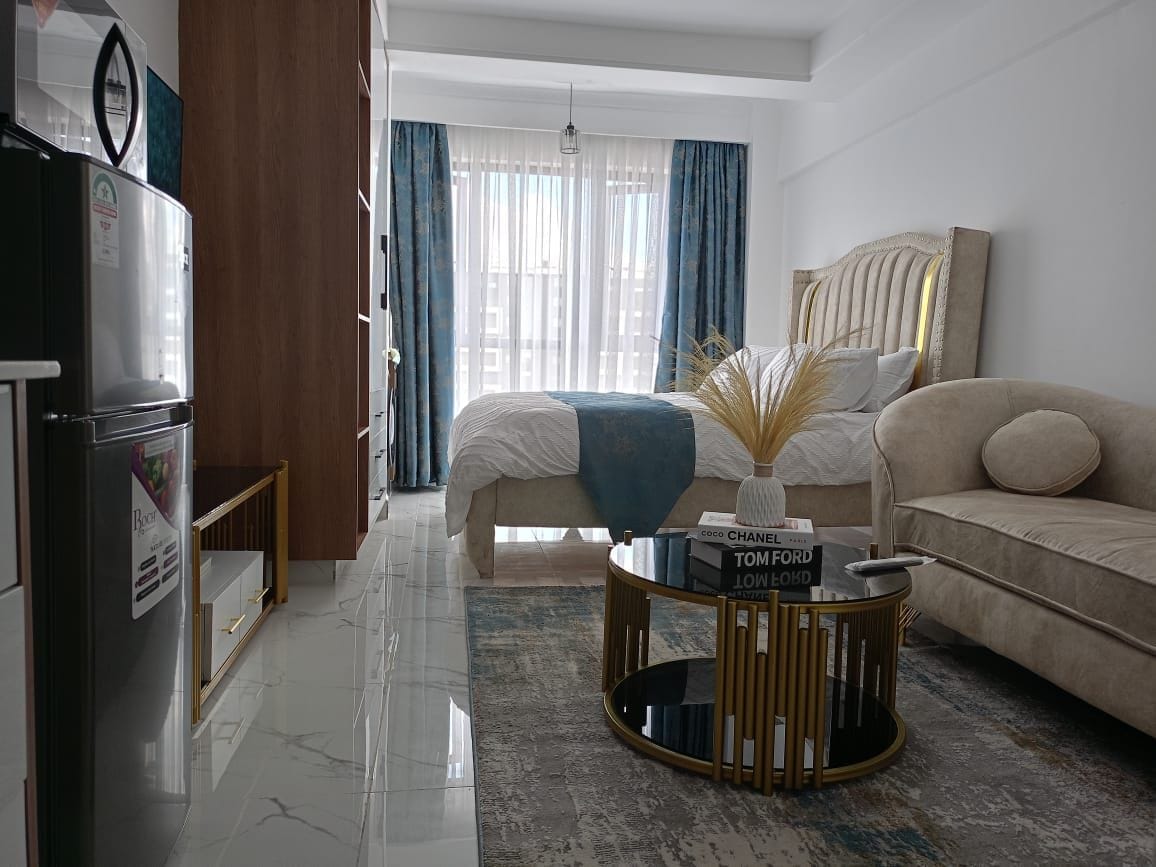 Une chambre d’hôtel moderne équipée d’un lit, d’un canapé, d’une table basse et d’un réfrigérateur.