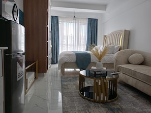 Une chambre d’hôtel moderne équipée d’un lit, d’un canapé, d’une table basse et d’un réfrigérateur.