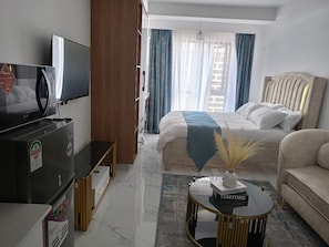 Une chambre d’hôtel équipée d’un lit, d’une télévision, d’un canapé et d’une table basse.