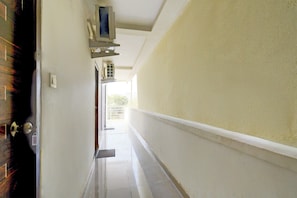 A corridor with a door on the left, a window on the right, and a vent on the ceiling. - Hotel O by OYO ELEGANT NEST Lemon Tree (Hyderabad)