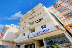 Een meerlaags hotelgebouw met balkons, een bordje met 'Elegant Nest' dat snel internet aangeeft, en een duidelijk zichtbaar 'HOTEL'-bord boven de ingang.
