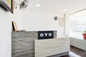 Een receptiebalie met een marmeren ontwerp, een klok en een bordje met de tekst 'OYO'.