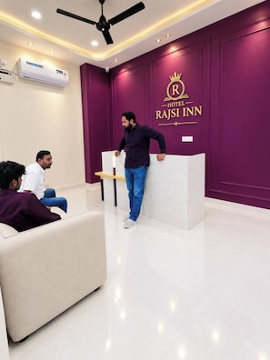 A hotel reception area with a reception desk, a ceiling fan, and an air conditioning unit. - Hotel Rajsi Inn (Faizabad)