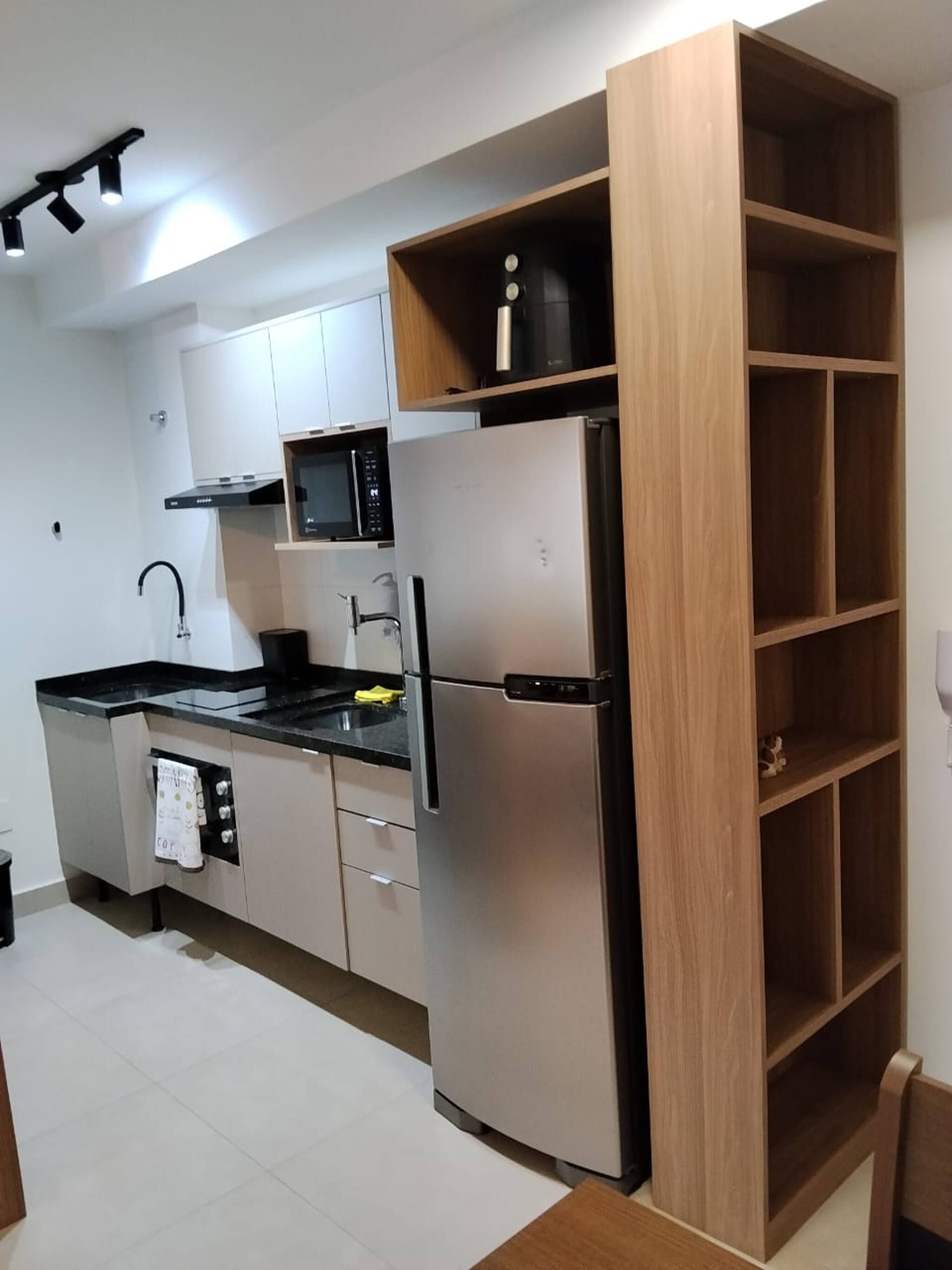 A compact kitchen with a stainless steel refrigerator, a microwave, and a sink.